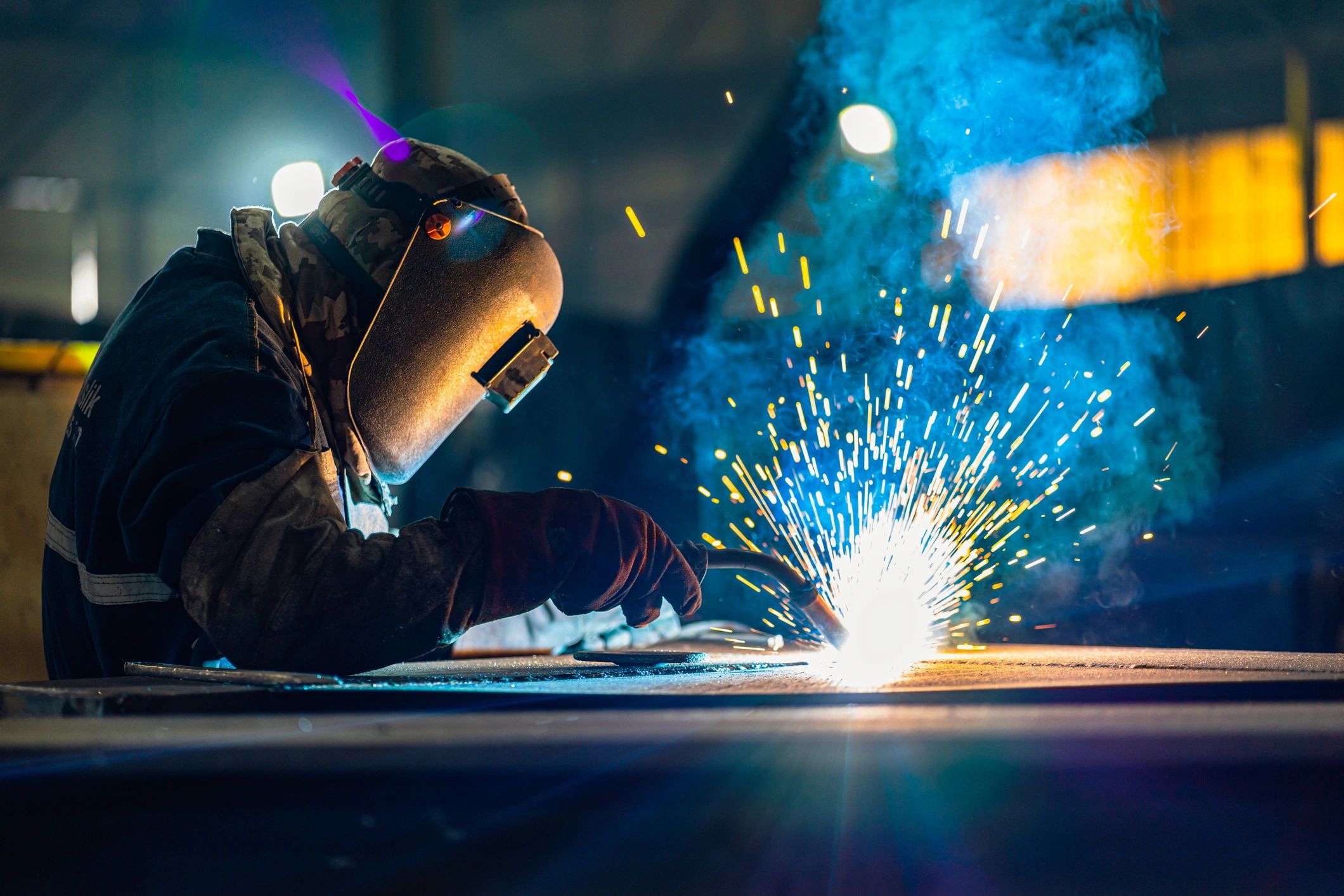 Welder wearing gloves holding a welding torch