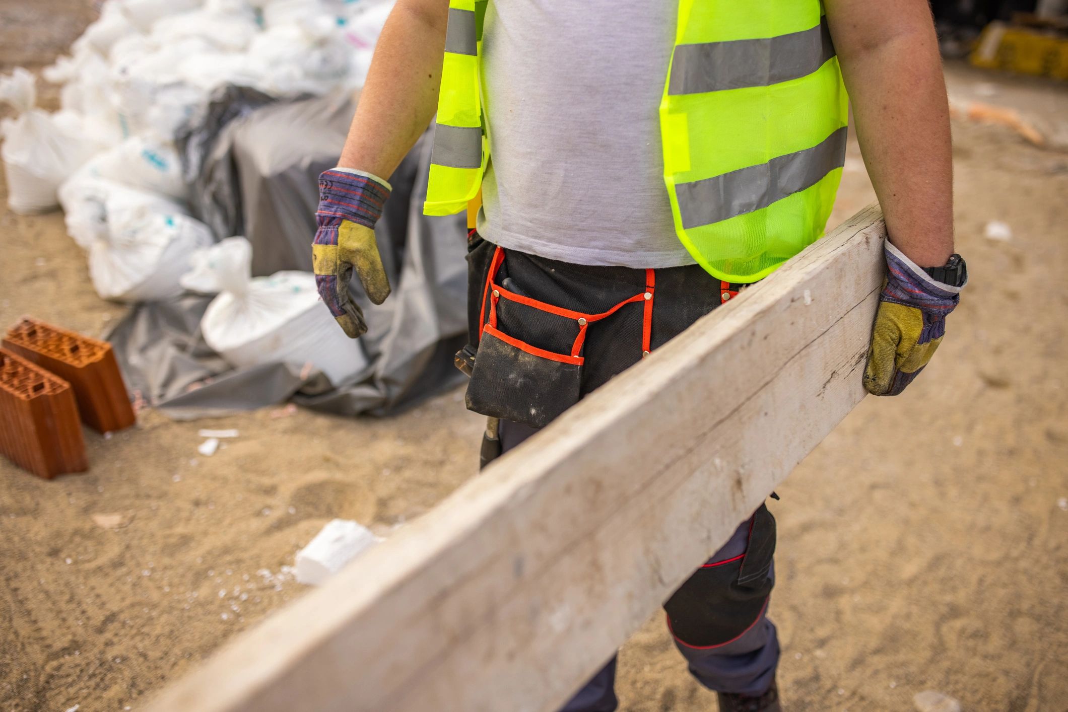 Construction worker carrying timber while wearing work gloves